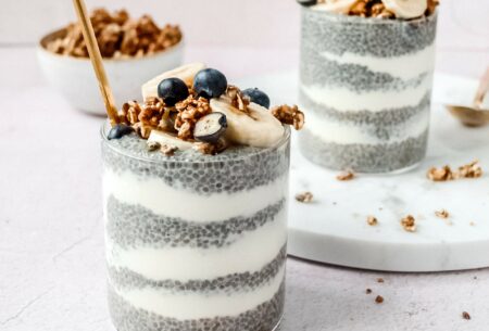 View Chia pudding A picture of two clear glass tumblers with thick layers of plain yoghurt and chia seeds with a sprinkle of granola, sliced bananas and blueberries on top