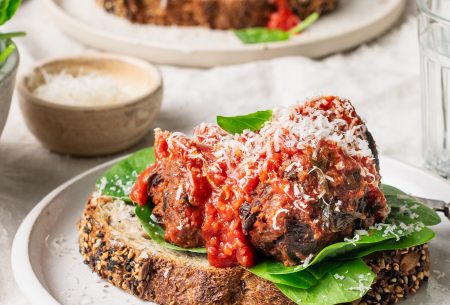 View Super Six Meatless meatballs A photo of the meatless meatballs set on a plate. It's been served on top of sourdough bread, spinach and a sprinkling of cheese.