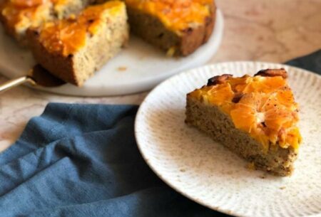 View Mixed citrus olive oil cake A mixed citrus olive oil cake with a plate in the forefront with a slice cut from the cake