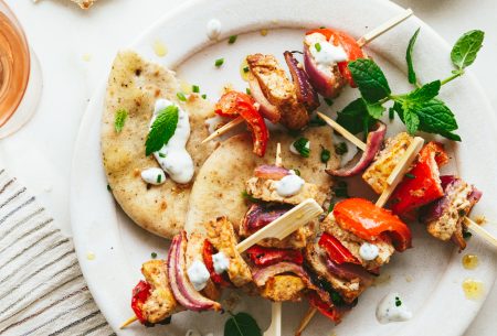 View Spiced tofu skewers with mint yoghurt Two spiced tofu skewers with mint yoghurt, shown on white plate with torn flatbread