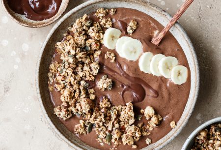 View Chocolate & banana smoothie bowl Chocolate and banana smoothie bowl topped with extra granola and banana, and a small pot of extra chocolate