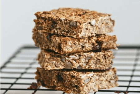 View Nutty banana fibre-filled flapjacks Four nutty banana fibre-filled flapjacks stacked on a wire cooling rack