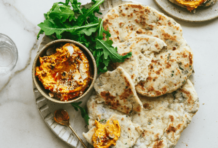 View ‘Live’ & herby flatbread with curried sweet potato dip Two fresh 'live' and herby flatbreads on a plate with a pot of curried sweet potato dip and fresh salad greens