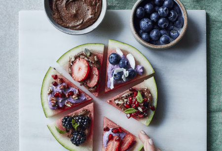 View Loaded prebiotic wedges Six slices of watermelon displayed on a plate in a circle, stacked with fresh fruits