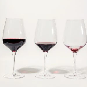 A photo of three glasses of wine with different amounts in them