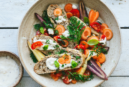 View Quick carrot caesar Ceramic bowl with quick carrot caesar salad, served with fresh brown bread slices and garnished with fresh mixed green herbs