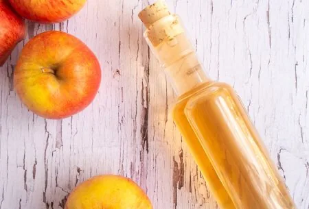 View Apple cider vinegar: the facts behind the fad Apple cider vinegar in a glass bottle on white wooden surface with fresh apples alongside