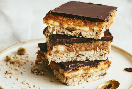 View Banoffee millionaires shortbread Three pieces of Banoffee millionaire shortbread stacked on a white plate