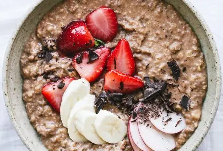View Creamy chocolate porridge One large bowl full of creamy chocolate porridge, topped with mixed fresh fruit and small chocolate chunk pieces