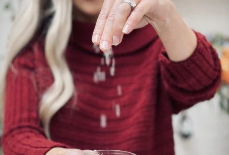 View Salt & the gut Megan Rossi with a small bowl of salt in one hand and spinkling it in the other hand
