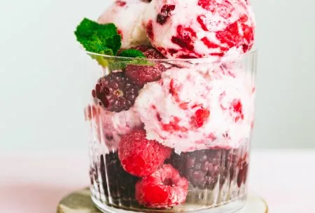 View Quick Kefir ice cream One glass jar overflowing with two large scoops of kefir ice cream. Garnished with frozen berries and fresh mint leaves