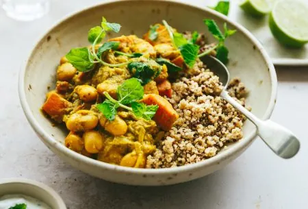View Sweet potato & butter bean curry with ‘live’ raita One bowl of cooked sweet potato and butter bean curry, with portion showing half grains and half curry. Served with a spoon