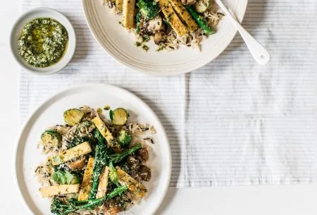 View Brussels sprouts & tenderstem broccoli with pesto & wild rice Two plates with Brussels sprouts & tenderstem broccoli & wild rice, served with a small pot of pesto between them