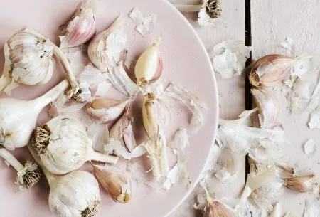 View Garlic & the low-FODMAP diet Garlic cloves and bulbs on plate and white wooden surface