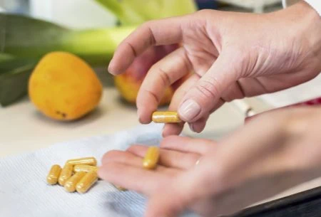View Postbiotics: a new word for your ‘Gutionary’! Two hands holding pill capsules over a chopping board