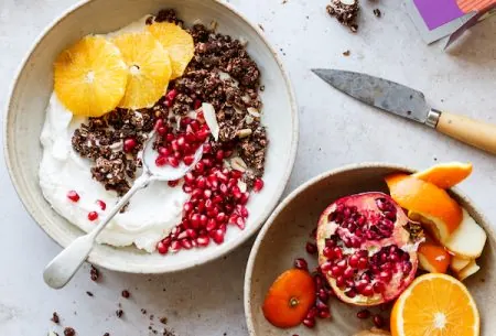 View Cocoa benefits A bowl of yogurt topped with granola and sliced orange and pomegranate seeds and a bowl with the remaining half a pomegranate and orange