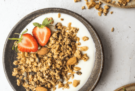 View Why we need mass reformulation of breakfast cereals Bowl of yogurt with granola and one fresh strawberry halved