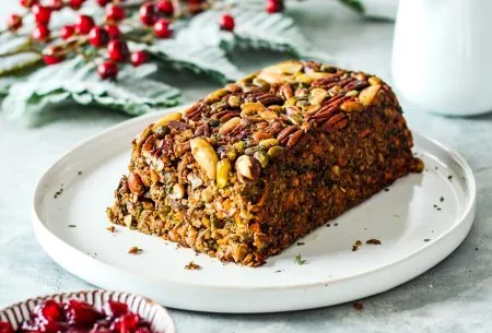 View Festive nut roast One entire baked festive nut roast, with end piece sliced off to show inside. Served with small pot of cranberry sauce