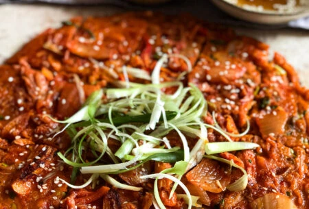 View Quick and easy kimchi pancakes Kimchi pancake with spring onion shavings and soy sauce dip in the background