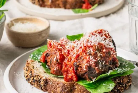 View Super Six Meatless meatballs A photo of the meatless meatballs set on a plate. It's been served on top of sourdough bread, spinach and a sprinkling of cheese.