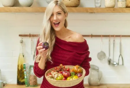 View 10 micro-habits for your microbes Dr Megan Rossi standing in kitchen holding a large bowl of mixed vegetables and smiling