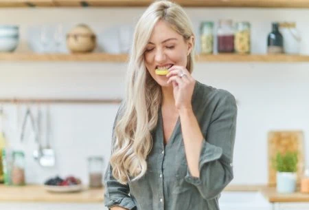 View Lemon water… magic or myth? Megan Rossi in kitchen slicing a lemon and eating it