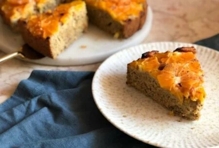 View Mixed citrus olive oil cake A mixed citrus olive oil cake with a plate in the forefront with a slice cut from the cake