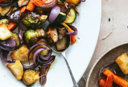 View Perfect roast potatoes & veg Large serving plate of perfect roast potatoes and mixed vegetables being served onto dinner plate