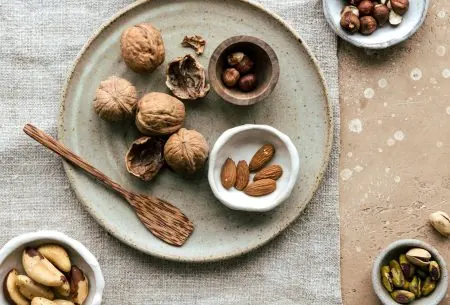 View Do you need to soak nuts & seeds? Ceramic plate on benchtop with natural linen cloth underneath and assortment of nuts and seeds