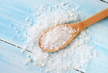 View Salt and gut health: should we be cutting down for our microbes too? Salt on a spoon and surrounding the spoon on a blue wooden surface