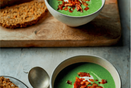 View Super green pea & ‘ham’ soup Two bowls of super green pea and ‘ham’ soup, with fresh bread on a chopping board
