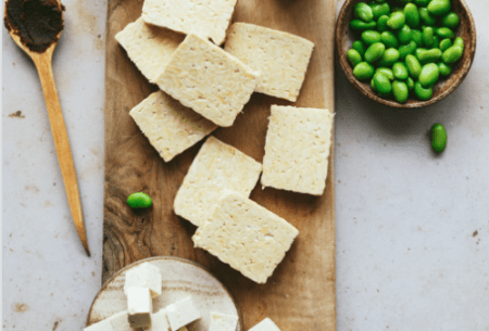 View Soya myths busted Chopping board on bench top with thick slices of tofu scattered and a small side pot of edamame beans
