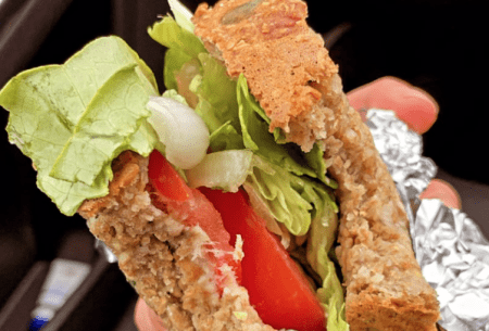 View Suspect a gluten intolerance? Find out what you should do Close up image of a hand holding a homemade sandwich with visible lettuce and tomato, wrapped in foil