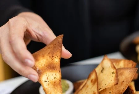 View 5 easy-to-follow tips for smart snacking A hand holding crackers with various dips available for snacking