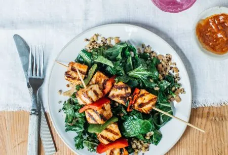 View Eating purely plant-based? Here are the key nutrients to consider A plate with quinoa, kale and veggie skewers on a wooden table with a white linen cloth and knife and fork, pink drink with ice and red dip