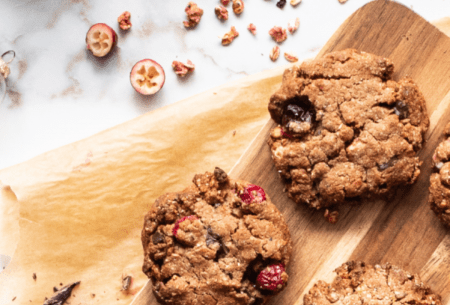 View Spiced cranberry & dark chocolate granola cookies Three spiced cranberry and dark chocolate granola cookies displayed on a chopping board