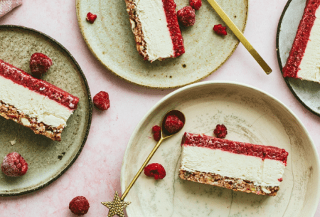 View Raspberry & cashew cheesecake Three slices of raspberry and cashew cheesecake on light green plates, with fresh raspberries scattered